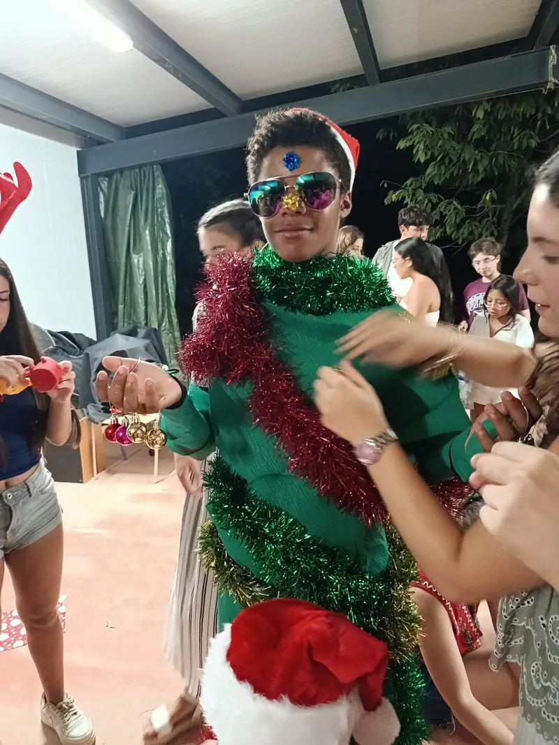 Un campista disfrazado de árbol de Navidad con espumillón
