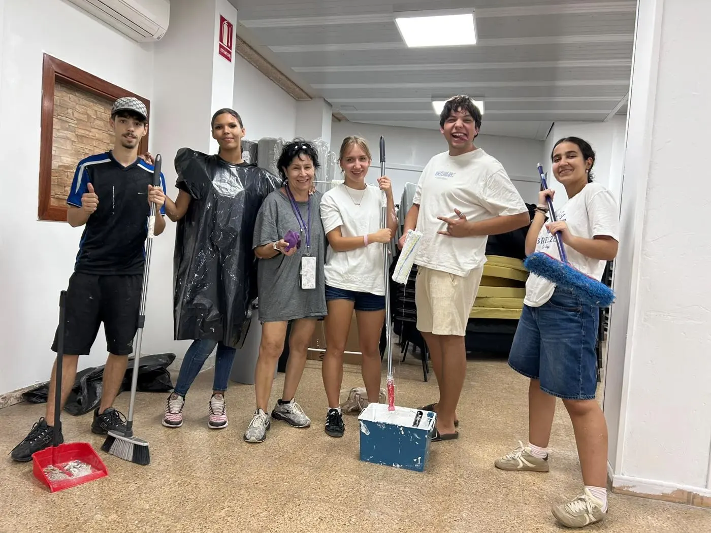 Voluntarios con escobas, rodillos y un cubo de pintura en el local de Barcelona