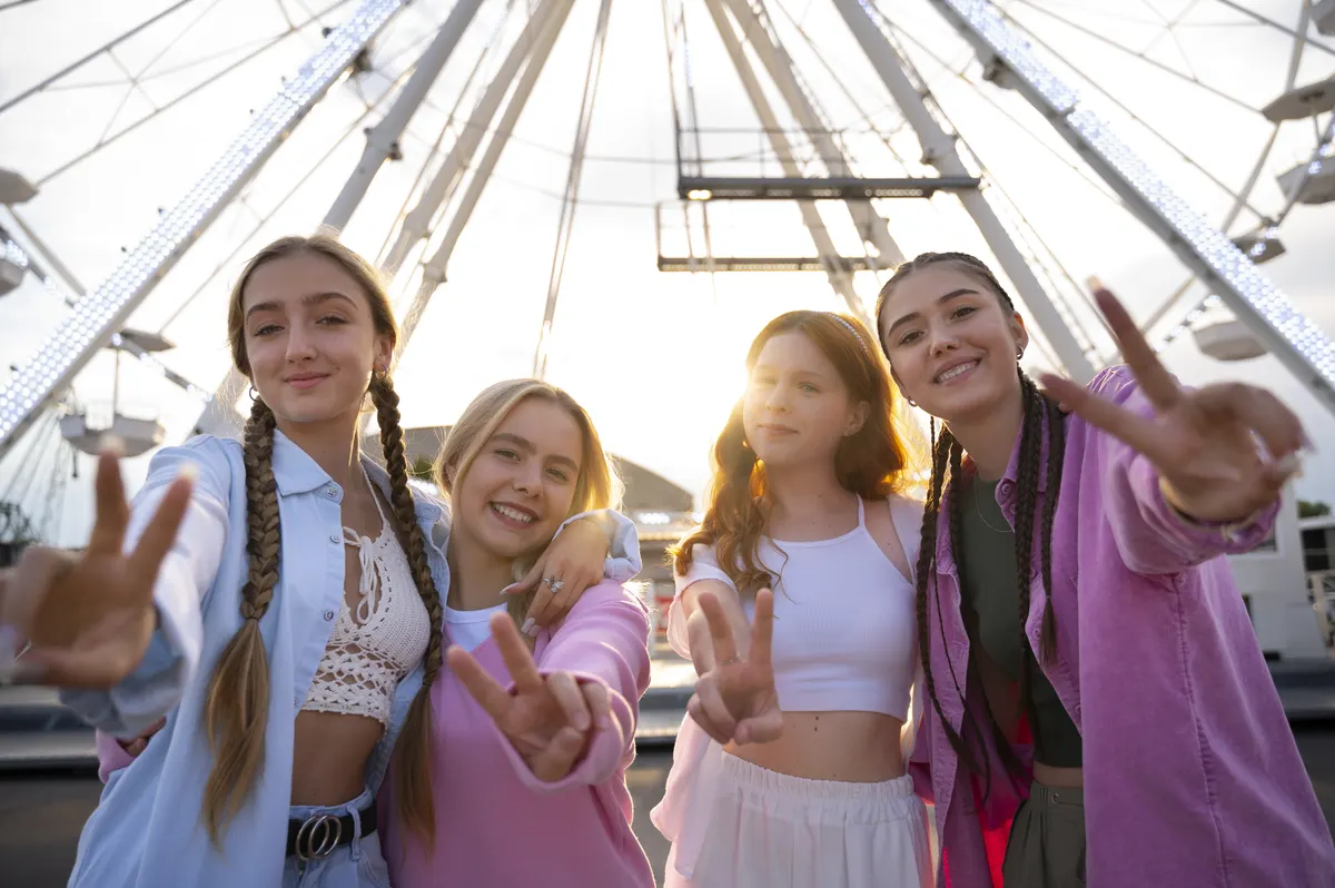 Cuatro chicas adolescentes sonríen al atardecer delante de una noria